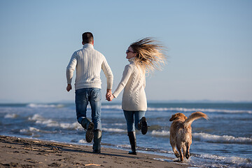 Image showing couple with dog having fun on beach on autmun day