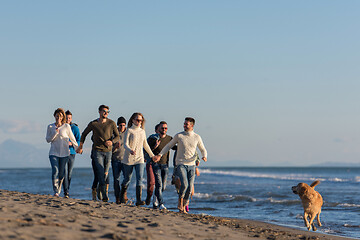 Image showing Group of friends running on beach during autumn day