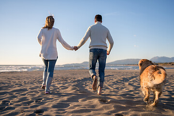 Image showing couple with dog having fun on beach on autmun day