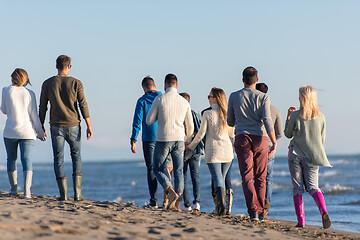 Image showing Group of friends running on beach during autumn day