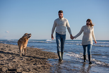 Image showing couple with dog having fun on beach on autmun day