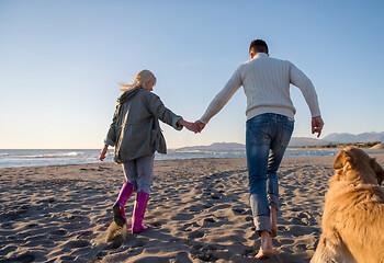 Image showing couple with dog having fun on beach on autmun day