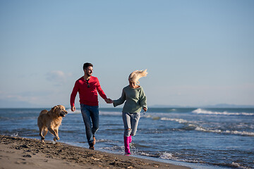 Image showing couple with dog having fun on beach on autmun day