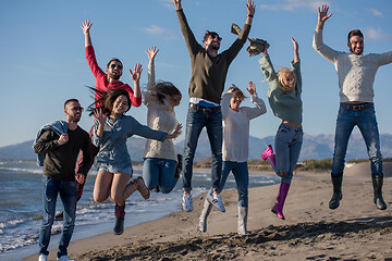 Image showing young friends jumping together at autumn beach