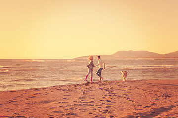 Image showing couple with dog having fun on beach on autmun day