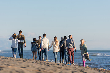 Image showing Group of friends running on beach during autumn day