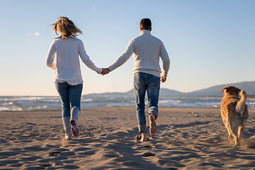 Image showing couple with dog having fun on beach on autmun day