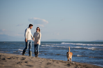 Image showing couple with dog having fun on beach on autmun day