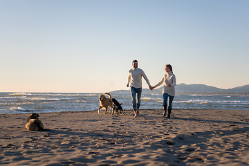 Image showing couple with dog having fun on beach on autmun day