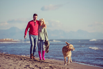 Image showing couple with dog having fun on beach on autmun day