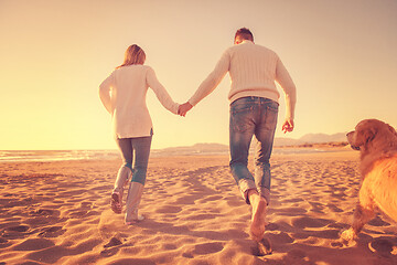 Image showing couple with dog having fun on beach on autmun day