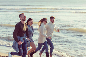 Image showing Group of friends running on beach during autumn day