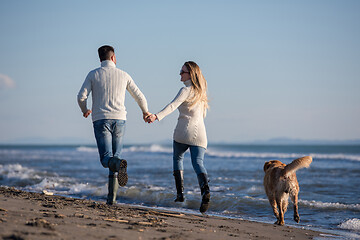 Image showing couple with dog having fun on beach on autmun day