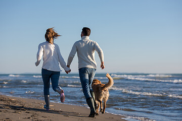 Image showing couple with dog having fun on beach on autmun day