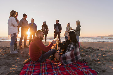 Image showing Couple enjoying with friends at sunset on the beach