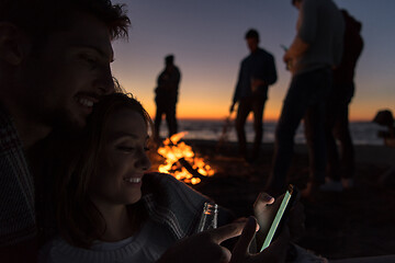 Image showing Couple enjoying bonfire with friends on beach