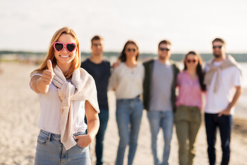 Image showing woman with friends on beach showing thumbs up