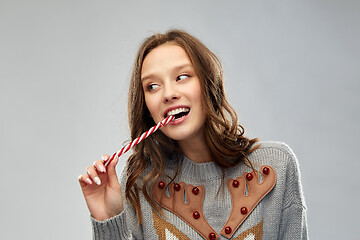 Image showing woman in christmas sweater eating candy cane