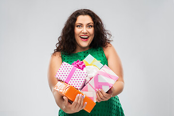 Image showing happy woman in green dress holding gift boxes