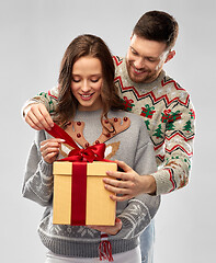 Image showing happy couple in christmas sweaters with gift box