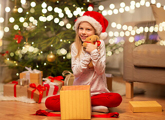 Image showing smiling girl in santa hat with christmas gift