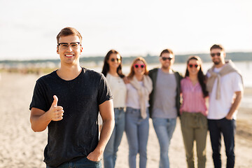 Image showing happy man with friends on beach showing thumbs up