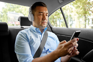 Image showing passenger with headphones using smartphone in car