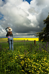 Image showing Country womanat farm gate watches the clouds over golden crops a