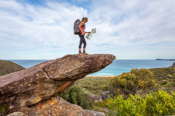 Image showing Hiker on a rock precipice holding a map