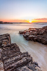 Image showing Shore waves rushing up the rock channel at sunrise