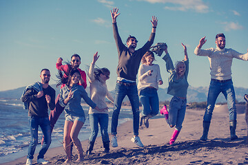 Image showing young friends jumping together at autumn beach