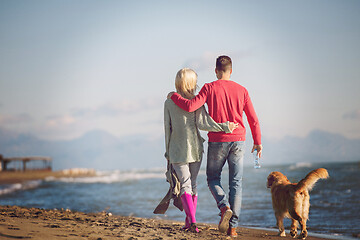 Image showing couple with dog having fun on beach on autmun day