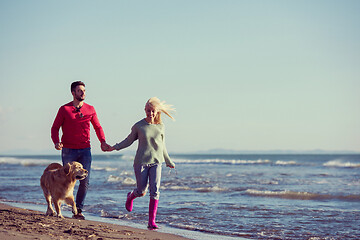 Image showing couple with dog having fun on beach on autmun day