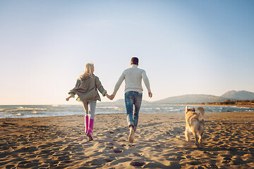 Image showing couple with dog having fun on beach on autmun day