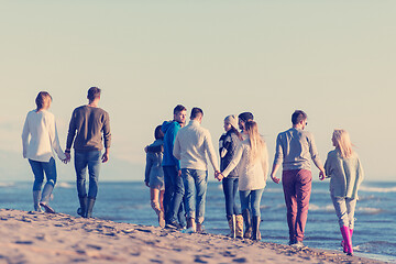 Image showing Group of friends running on beach during autumn day