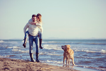 Image showing couple with dog having fun on beach on autmun day