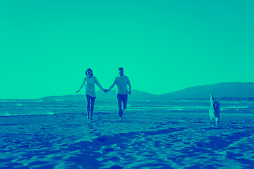 Image showing couple with dog having fun on beach on autmun day