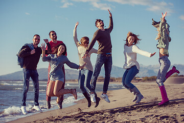 Image showing young friends jumping together at autumn beach