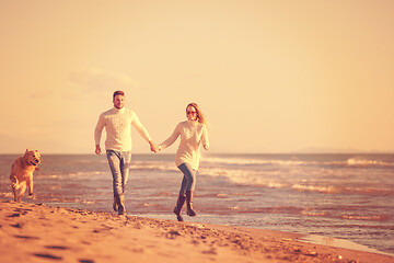 Image showing couple with dog having fun on beach on autmun day