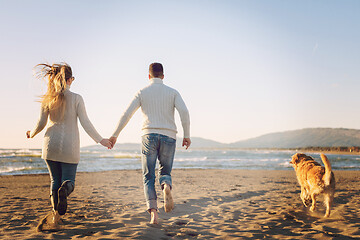 Image showing couple with dog having fun on beach on autmun day