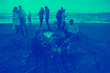 Image showing Couple enjoying with friends at sunset on the beach