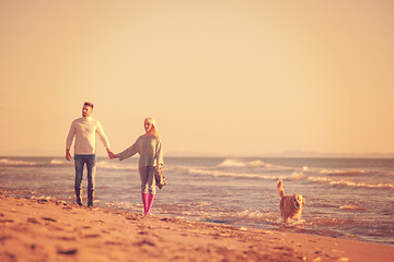 Image showing couple with dog having fun on beach on autmun day