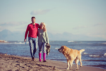 Image showing couple with dog having fun on beach on autmun day