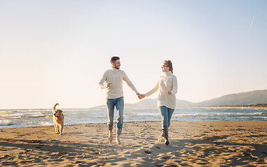 Image showing couple with dog having fun on beach on autmun day