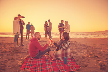 Image showing Couple enjoying with friends at sunset on the beach