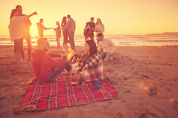 Image showing Couple enjoying with friends at sunset on the beach