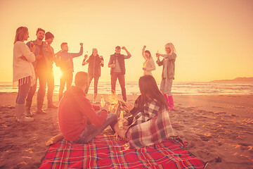 Image showing Couple enjoying with friends at sunset on the beach