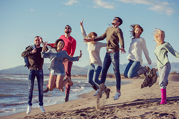 Image showing young friends jumping together at autumn beach