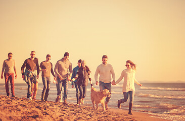 Image showing Group of friends running on beach during autumn day