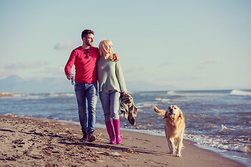 Image showing couple with dog having fun on beach on autmun day